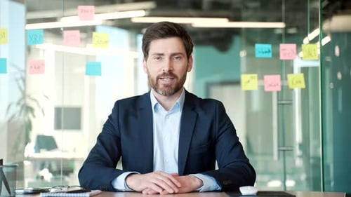 Webcam view. Handsome businessman talking on a video call looking at camera sitting in office. A man
