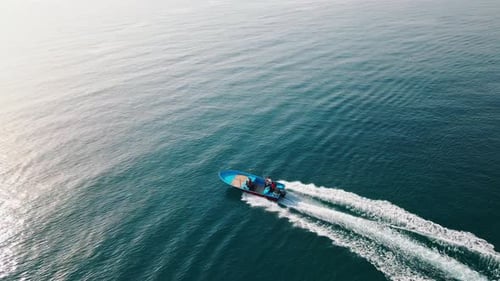 Drone shot of a high-speed boat leaving a curved trail in the ocean