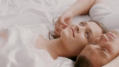 Junges Paar entspannt sich zusammen im Bett und teilt einen Moment der Liebe und Intimität