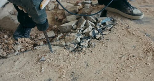 Worker Breaks Concrete with a Jackhammer Indoors