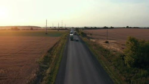 Aerial view of road at farmland near fields with cars passing by