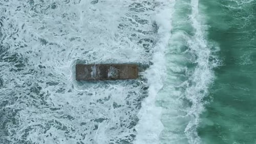 Aerial Video of Wooden Jetty Reaching Into Open Water With Waves Rolling Below and Sunbathers Above