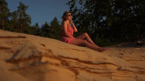Woman Sitting on Sand Dune at Sunset