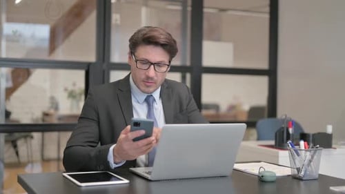 Businessman Using Smartphone While Working at Desk
