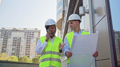 Architects Reviewing Blueprints on a Phone at Construction Site