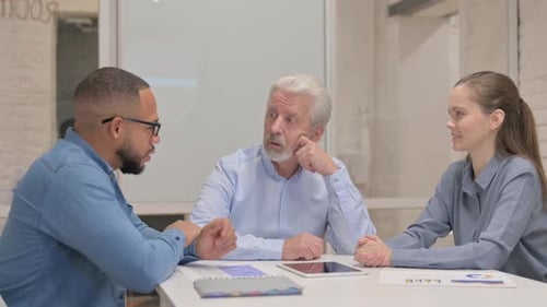 Senior Businessman Talking with Young Man in Office
