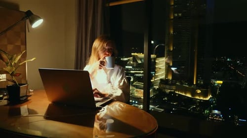 Business Woman Working Late at Night in Hotel Room Overlooking Cityscape Worklife Balance