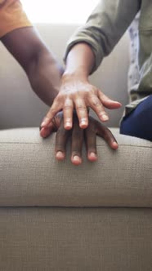 Vertical video: Couple holding hands on couch, showing affection and support at home