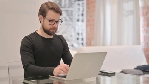 Man Typing on Laptop Computer at Glass Table
