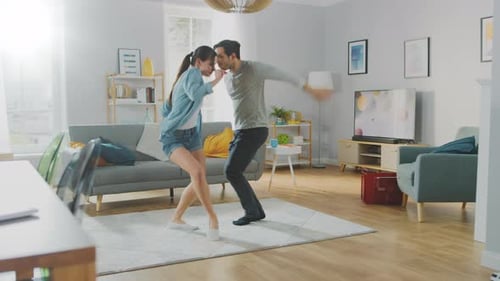 Playful couple dancing together in modern living room
