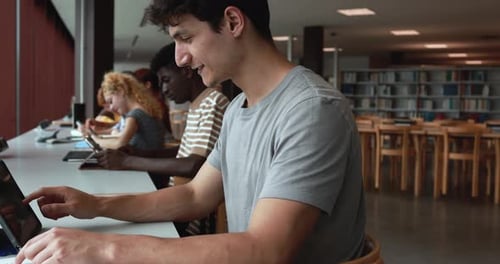 Groupe de jeunes étudiants apprenant ensemble à l'intérieur de la bibliothèque de l'école
