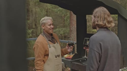 Adults Enjoying Outdoor Barbecue in Forested Area