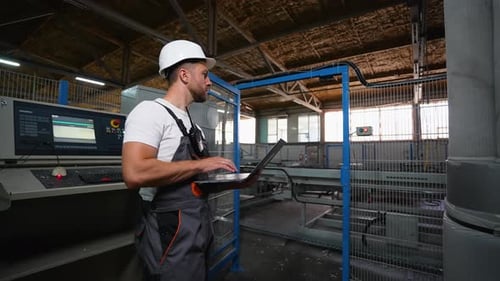 Ingenieurprogrammierer mit Laptop in einer Industriefabrik analysiert den Produktionsprozess