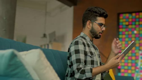 Young Adult Using Tablet on Sofa at Home