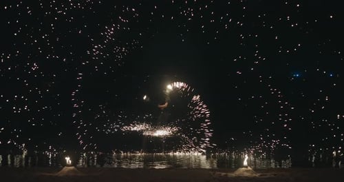 Fire Show Performer Spins Burning Poi Creating a Huge Circle of Sparks on a Night Beach Above Water