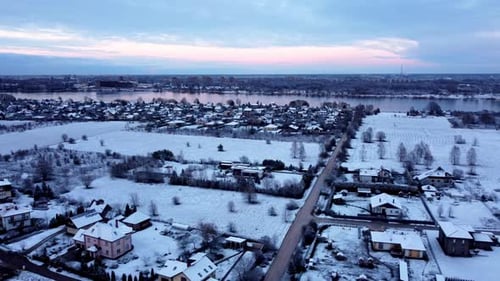 Aerial Winter Sunset Over Snowy Suburban Neighborhood Near Icy River