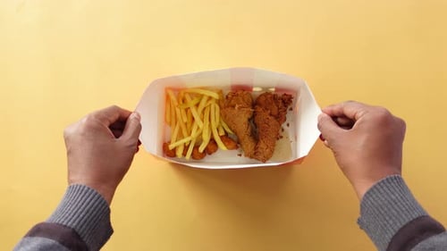Top View of Hand Pick Crispy Fried Chicken From a Paper Box