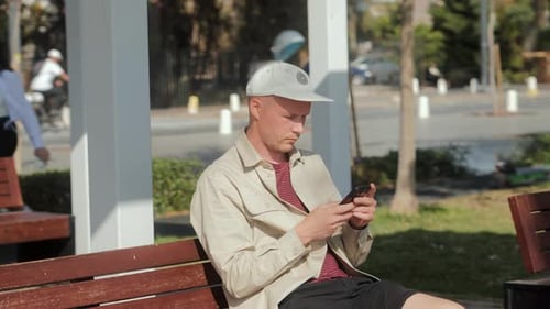 Young Adult Using Smartphone on Park Bench