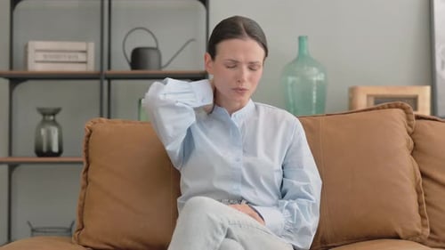 Woman Rubbing Neck in Pain on Couch