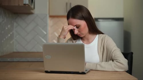 Tired Young Adult Woman at a Laptop