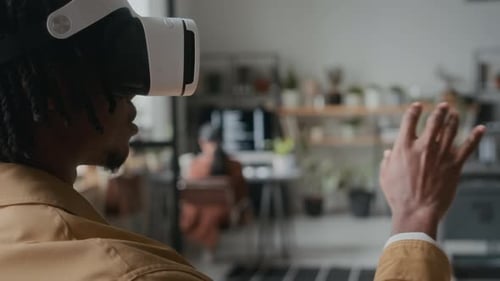 Schwarzer Mann mit VR-Headset testet Virtual-Reality-Anwendung im Büro