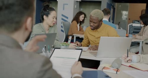 Mixed Race Group of Employees Talking and Using Laptops in Creative Office Room