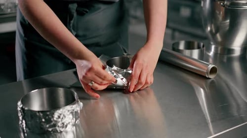Close Up Hands Baker in Professional Kitchen Wraps the Pans with Foil Before Pouring the Dough Onto