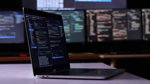 Vista de perto do monitor de um laptop mostrando o código na mesa na frente de vários monitores com banco de dados