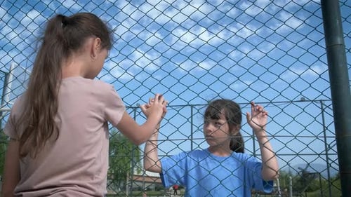 Children Holding Hands Through Chain Link Fence