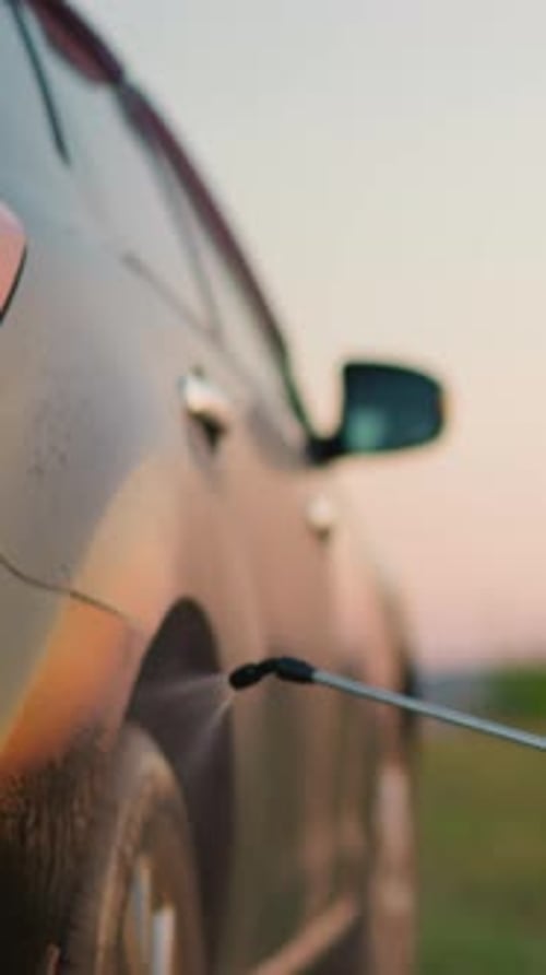 Little Kid Sprays Water on Parents Car in Field