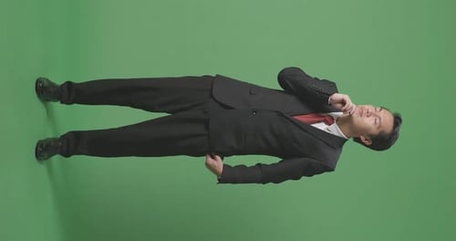 Ein asiatischer Geschäftsmann, der über etwas nachdenkt und sich auf dem Greenscreen im Studio umschaut