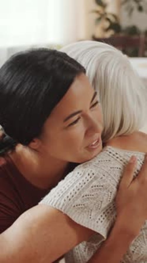 Young Woman Comforts Senior Woman With Loving Hug
