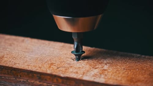 CloseUp of Unscrewing the Screw From a Block of Wood With a Screwdriver