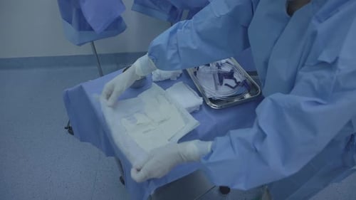 Eine Krankenschwester bereitet in einem chirurgischen Operationssaal ein Tablett mit medizinischen Geräten vor