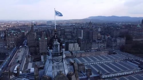 A panoramic view of Edinburgh, Scotland, with the iconic Scottish flag flying high. The city skyline
