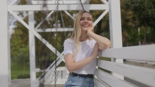 Woman Smiling and Sitting on Swing in Park