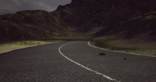 Winding Road Through Mountainous Terrain Under a Dusky Sky at Twilight