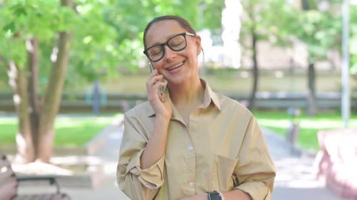 Multi Ethnic Woman Talking on a Smartphone in a Park