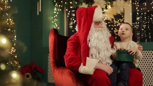 Boy with Present Sitting with Santa Claus Indoors