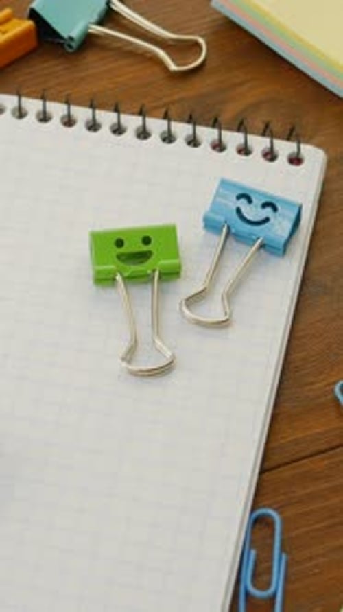 Green and Blue Metal Smile Binder Clip on Paper Notebook