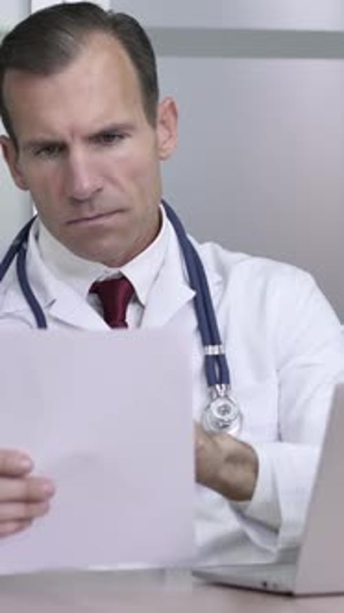 Médecin travaillant sur des documents et un ordinateur portable, rapport médical, Vidéo verticale