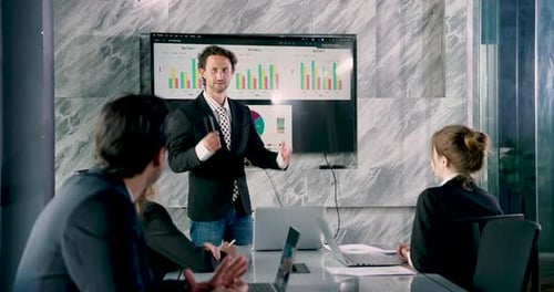 Caucasian businessman confidently presenting project data to multiracial team seated in office
