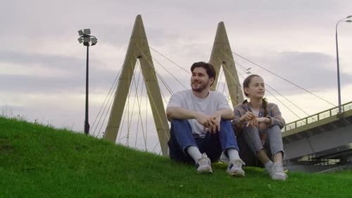 Guy is Sitting in the Park with a Girl and He's Gently Putting His Arm Around Her Shoulder Getting