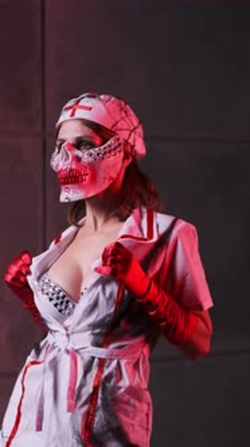 Beautiful sexy girl in scary nurse costume, red gloves and scary mask for Halloween on black backgro
