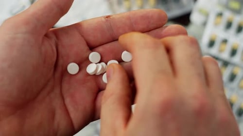 Hand Holding White Round Pills Close Up