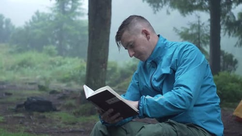 A Tourist in a Camp Near a Tent Reads a Book