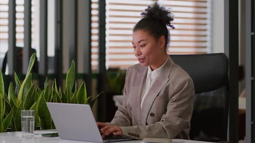 Woman Works on Laptop During Video Call in Office