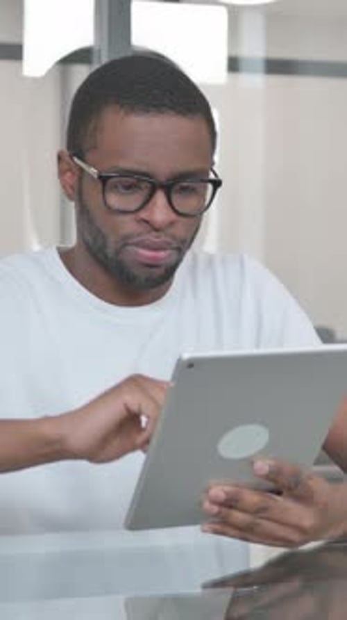 Young African Man Using Digital Tablet in Office, vertical video