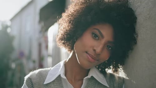 Atractiva chica afroamericana sonriendo relajándose bajo la luz del sol del verano al aire libre