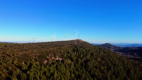 Aerial drone footage of a wind turbines on mountain ridges generating renewable energy.